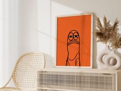 an orange poster with a cartoon character on it next to a white chair and plant