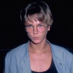 a woman wearing glasses in front of a black background