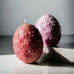 two pink apples sitting next to each other on a white surface with a knife in front of them