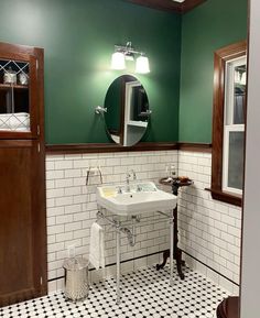 a white sink sitting under a bathroom mirror next to a wooden cabinet in a green room