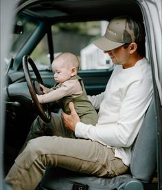 a man sitting in the driver's seat of a truck holding a small child