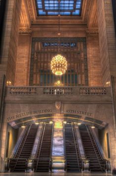 there is a chandelier hanging above the escalators in this large building