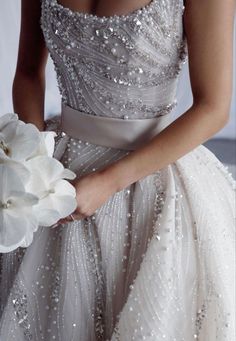 a woman in a wedding dress holding a white flower