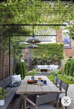 an outdoor dining area with wooden table and benches under a pergolated trellis