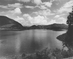 a lake surrounded by mountains under a cloudy sky