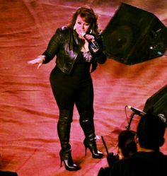 a woman standing in front of a microphone on top of a red carpeted floor