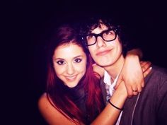 a young man and woman are posing for a photo in front of a dark background