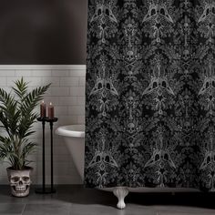 a black and white shower curtain with skulls on it next to a bathtub in a bathroom