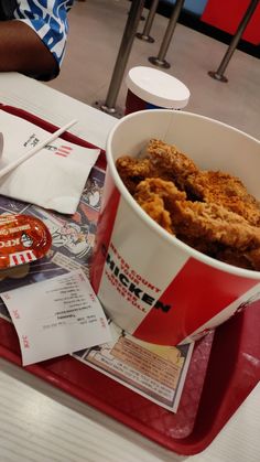 a tray that has some food on top of it and sauce in a cup next to it