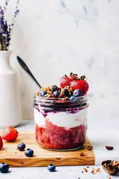 a jar filled with yogurt and berries on top of a wooden cutting board