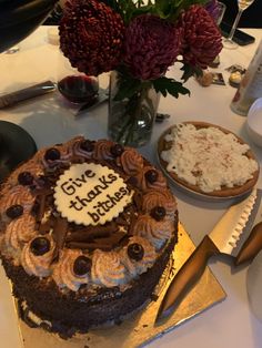 a chocolate cake sitting on top of a table next to a vase with flowers in it