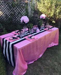 the table is set with pink and black linens