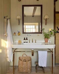 a white sink sitting under a mirror in a bathroom next to a towel rack and potted plant