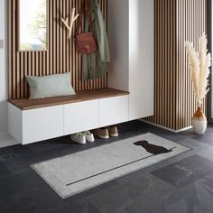 an entryway with a bench, rug and coat rack