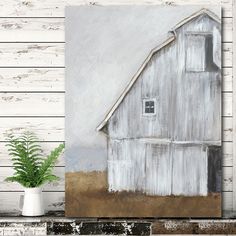 a painting of a white barn on a wooden wall next to a potted plant