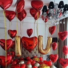 red and gold balloons with the word u on them are floating in the air above a bed