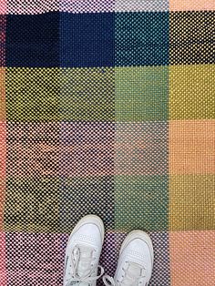 a pair of white shoes sitting on top of a colorful rug