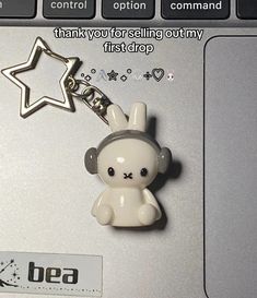 a keychain with a small white teddy bear on it's front and side