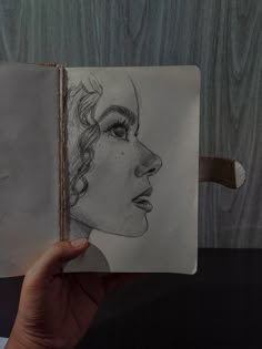 a drawing of a woman's face is shown in a book with the pages open