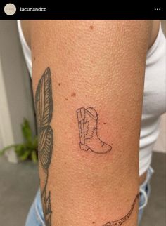 a tattoo on the arm of a woman with a cowboy boot and arrow in it