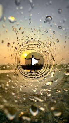 a person holding a surfboard while standing in the middle of an ocean with drops of water on it