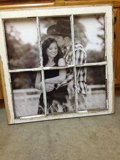 an old window frame with a couple kissing in front of it and some wooden cabinets