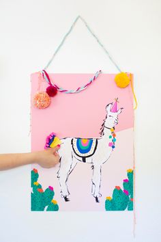 a person holding up a pink poster with a llama on it's back