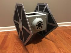 a paper model of a star wars tie that is sitting on the floor in front of a wall