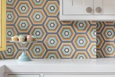 an image of a kitchen setting with cupcakes on the counter and hexagonal wallpaper