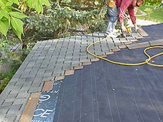 two men are working on the roof of a house