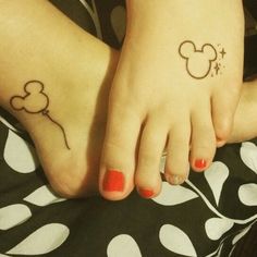 two feet with mickey mouse tattoos on them