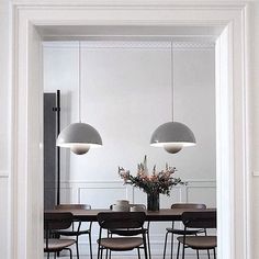 the dining room table is surrounded by four chairs and two pendant lights above it are flowers