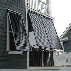 an open window on the side of a gray house with white railing and balconies