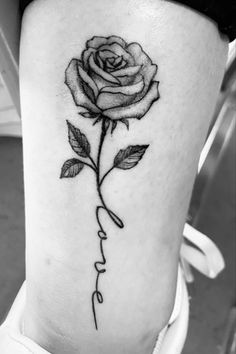 a black and white photo of a rose with the word love tattooed on its side