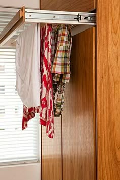 an open closet door with clothes hanging from it's sides and on the bottom shelf