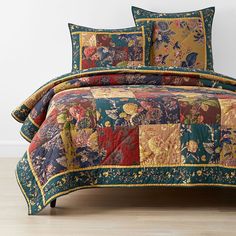 a bed covered in a multicolored patchwork comforter and matching pillow cases