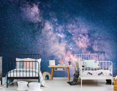 a bedroom with a bed, desk and night sky wall mural on the wall behind it