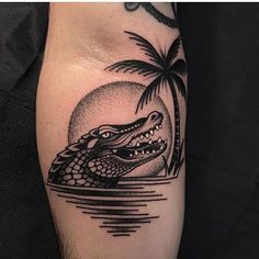 a black and white photo of an alligator on the arm with palm trees in the background