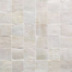 a white tiled wall with small squares on it