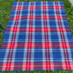 a blue and red plaid blanket laying on the grass