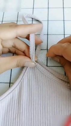 two hands are working on a piece of fabric that is being sewn together with scissors