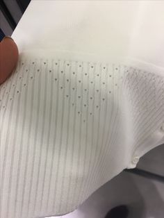 someone is holding the bottom of a white shirt with holes on it's sleeves