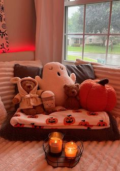 two teddy bears sitting on top of a bed next to candles and pumpkins in front of a window