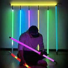 a man sitting on the floor holding two lightsabes in front of his face