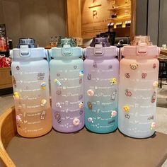 four different colored water bottles sitting on top of a table