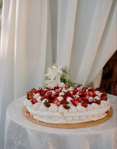 a white cake with strawberries on top sitting on a table