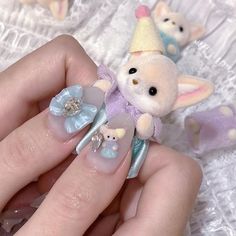 a person holding a small stuffed animal in their hand with some fake nails on it