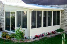 a white sun room sitting on top of a lush green field