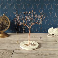 a wire tree with tiny birds on it sitting on a table next to a globe