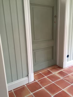 an open door in a room with red tiles on the floor and white painted walls